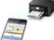 Un smartphone controlla wireless una stampante che emette documenti stampati a colori. Sullo schermo del cellulare è visibile l'app 'Epson Smart Panel'.