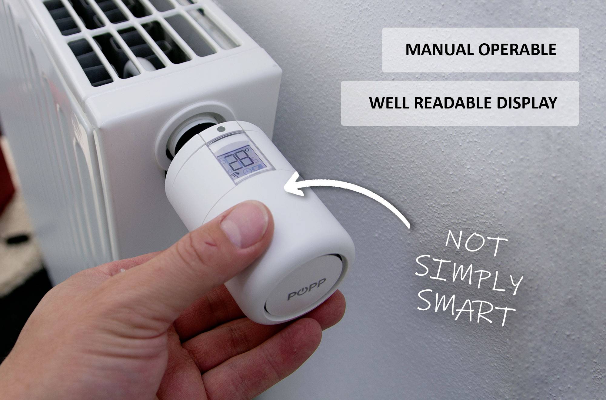 Una mano ruota il display di un termostato intelligente su un radiatore. Testo: 'Azionabile manualmente', 'Display ben leggibile' e 'Non semplicemente intelligente'.