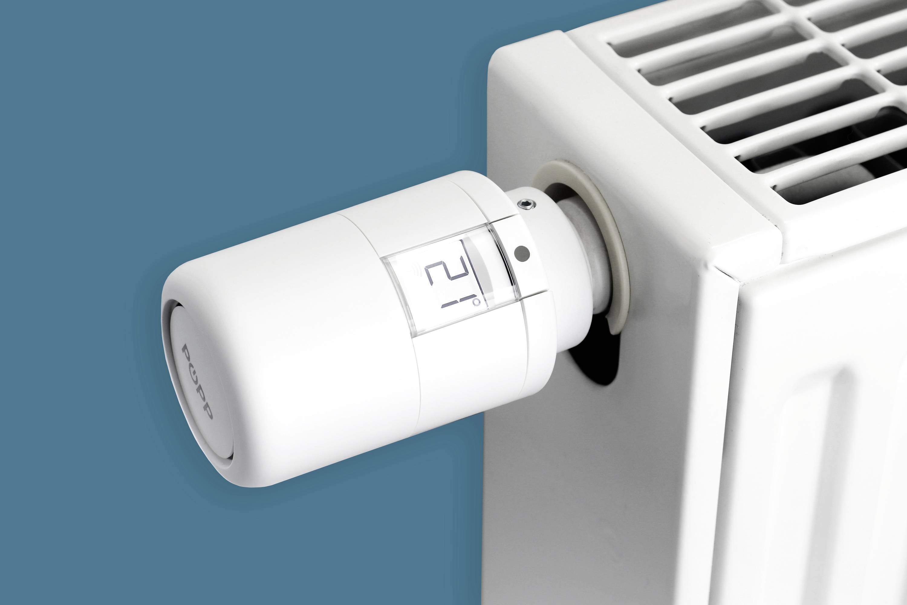 Un radiatore bianco con valvola termostatica impostata sul livello 2 su uno sfondo turchese.