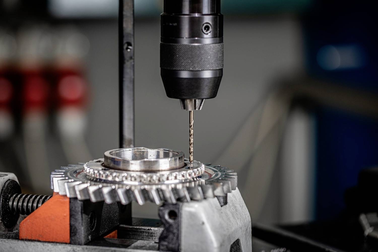 Una macchina utensile sta lavorando un ingranaggio in un laboratorio. Il trapano è posizionato con precisione sul metallo. Dettaglio meccanico visibile.