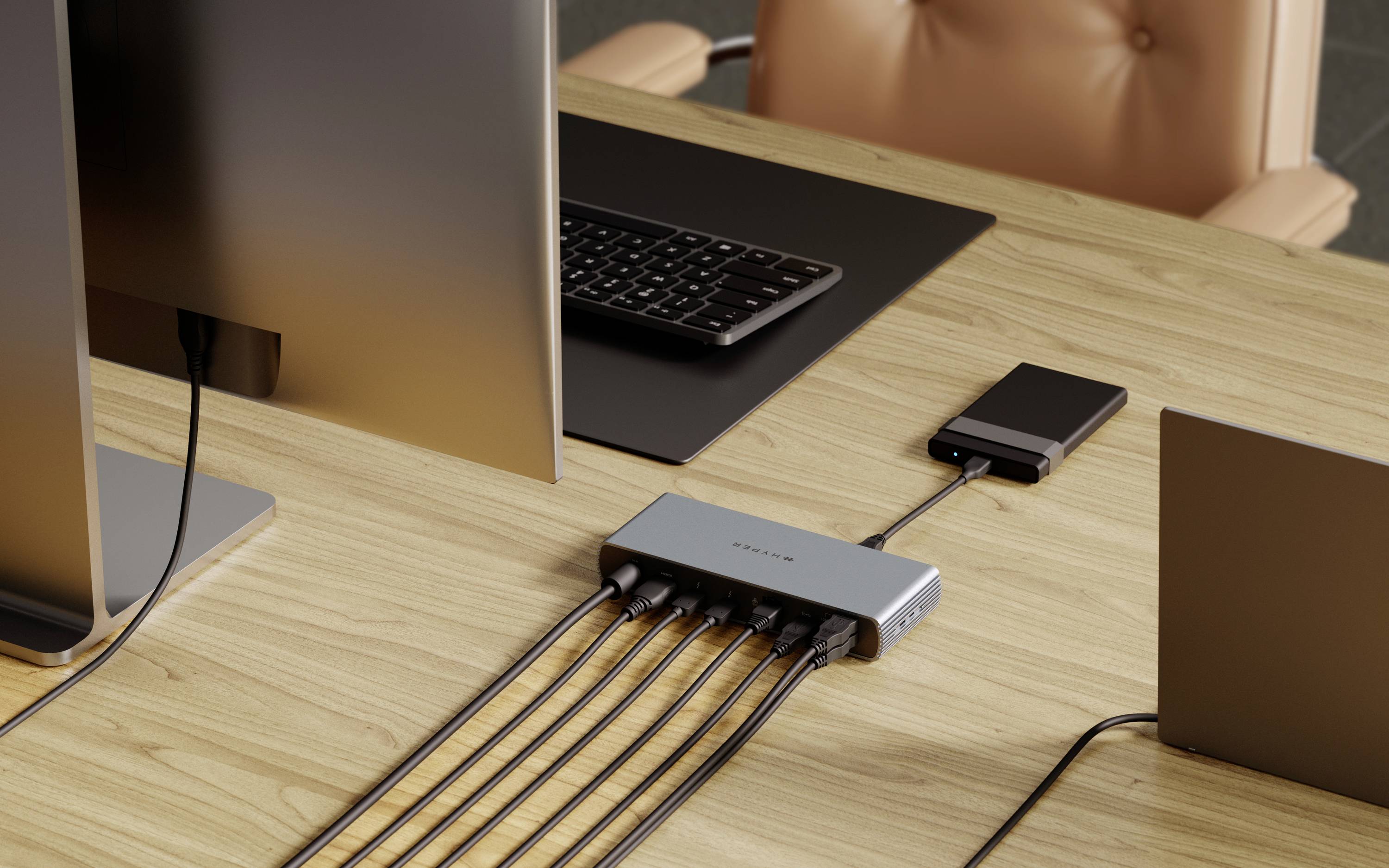 Una scrivania con un laptop, un monitor, una tastiera, uno smartphone e un hub USB a cui sono collegati diversi cavi.