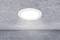 Una lampada da soffitto bianca e rotonda illumina un ambiente con struttura di soffitto e pareti grigie.
