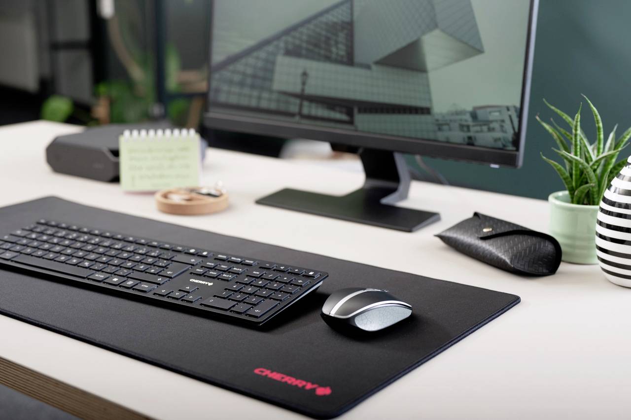 Ufficio moderno con schermo, tastiera e mouse su una scrivania; immagine di architettura moderna sullo sfondo dello schermo.