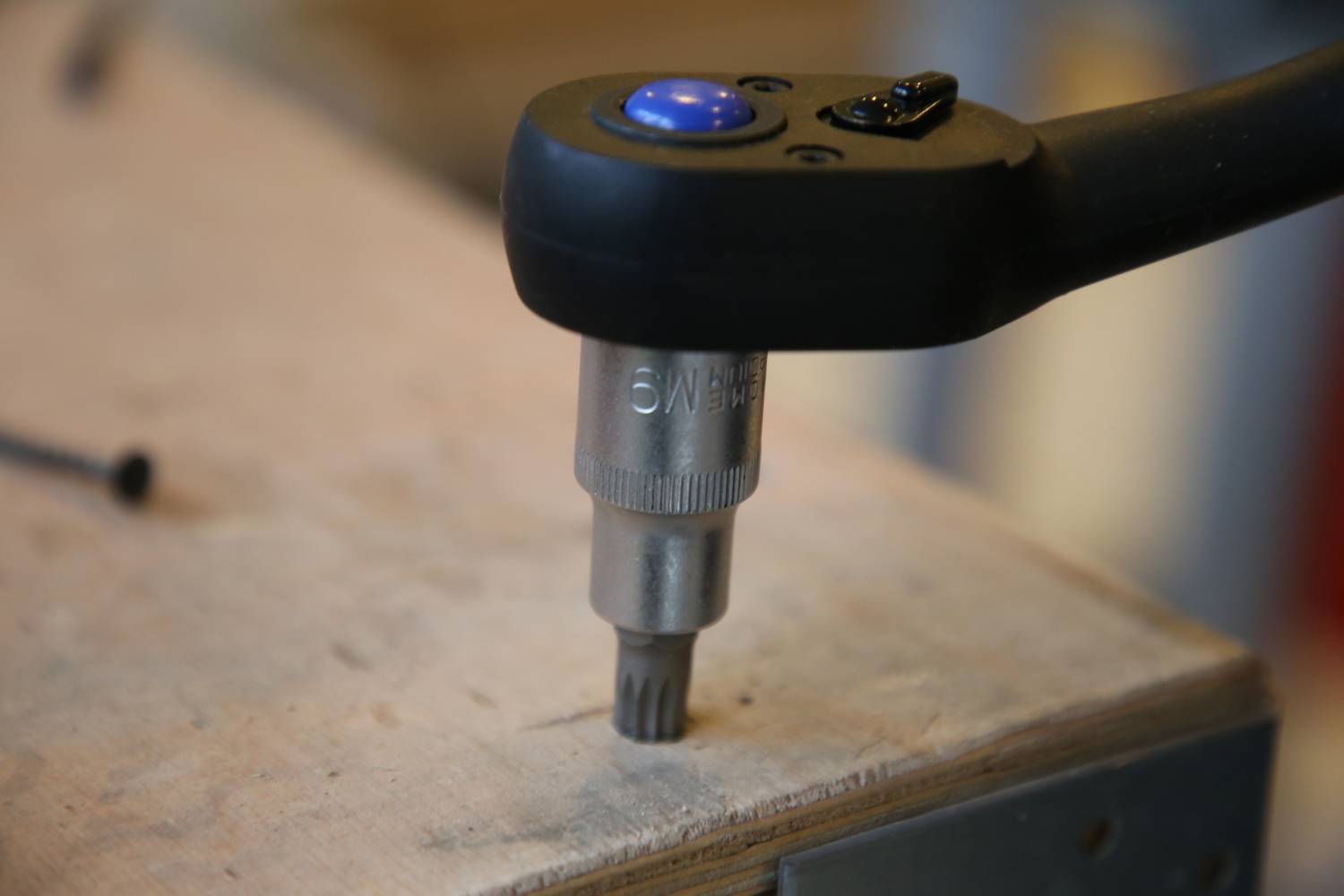 'Avvitatore elettrico avvita una vite in una tavola di legno.' Il primo piano mostra l'avvitatore al lavoro sulla superficie di un tavolo di legno.