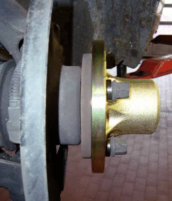 Primo piano di un mozzo ruota con disco freno e cuscinetto su un veicolo. Viti arrugginite e superfici metalliche mostrano segni di usura.