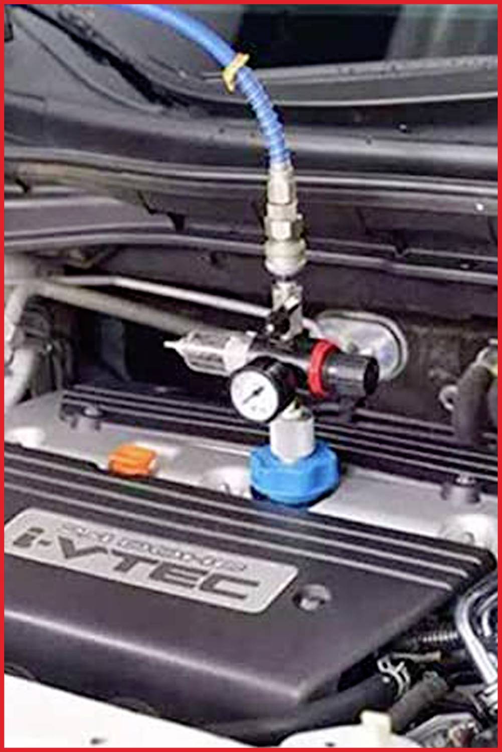 Un vano motore con un attrezzo blu collegato alla copertura del motore. Un manometro e alcuni tubi sono visibili.