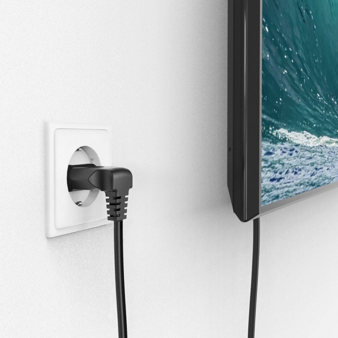 Presa elettrica con spina inserita accanto a un televisore che mostra un'immagine di onde nell'oceano.