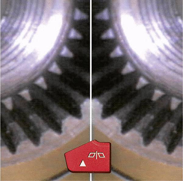 Primo piano di due ingranaggi: a sinistra con usura, a destra intatto. Un simbolo rosso indica l'avviso di usura.