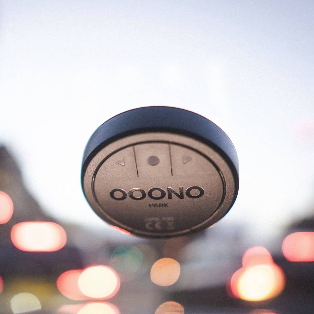 Un dispositivo elettronico rotondo con la scritta 'OONO' è fissato a un parabrezza, con luci sfocate sullo sfondo.