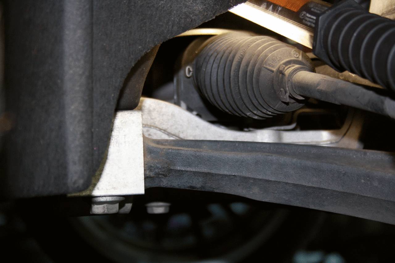 Un primo piano di un componente automobilistico che mostra un giunto e alcuni fissaggi, probabilmente una parte della sospensione o dello sterzo.
