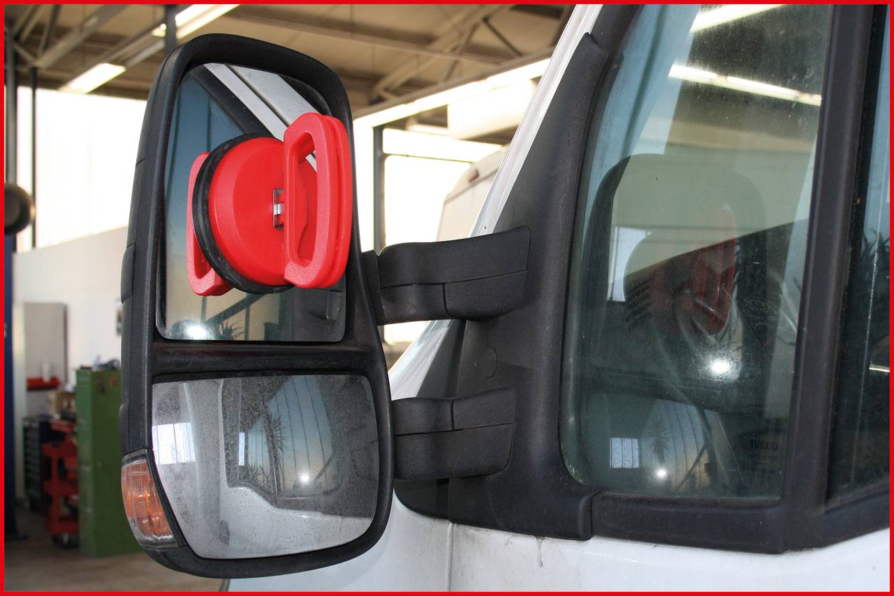 Catenaccio di sicurezza rosso su uno specchio laterale di un camion in un'officina.