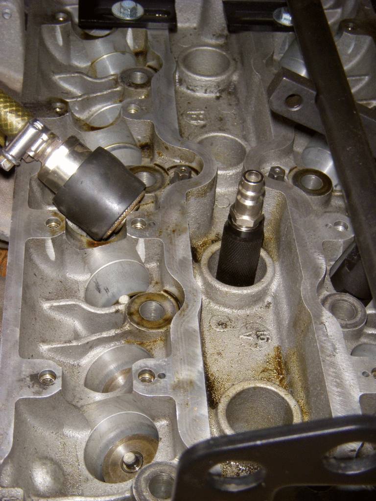 Blocco motore aperto di una macchina con candele di accensione e parti metalliche visibili. Sono in corso lavori di manutenzione.