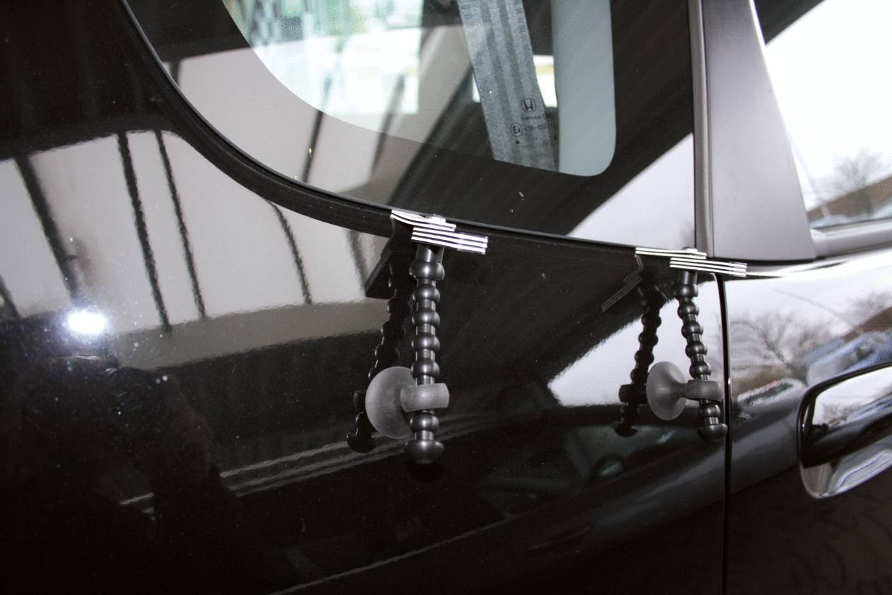 Un'auto con supporti speciali sul finestrino laterale. I supporti tengono dei forti ventose che sono fissate al vetro della finestra.