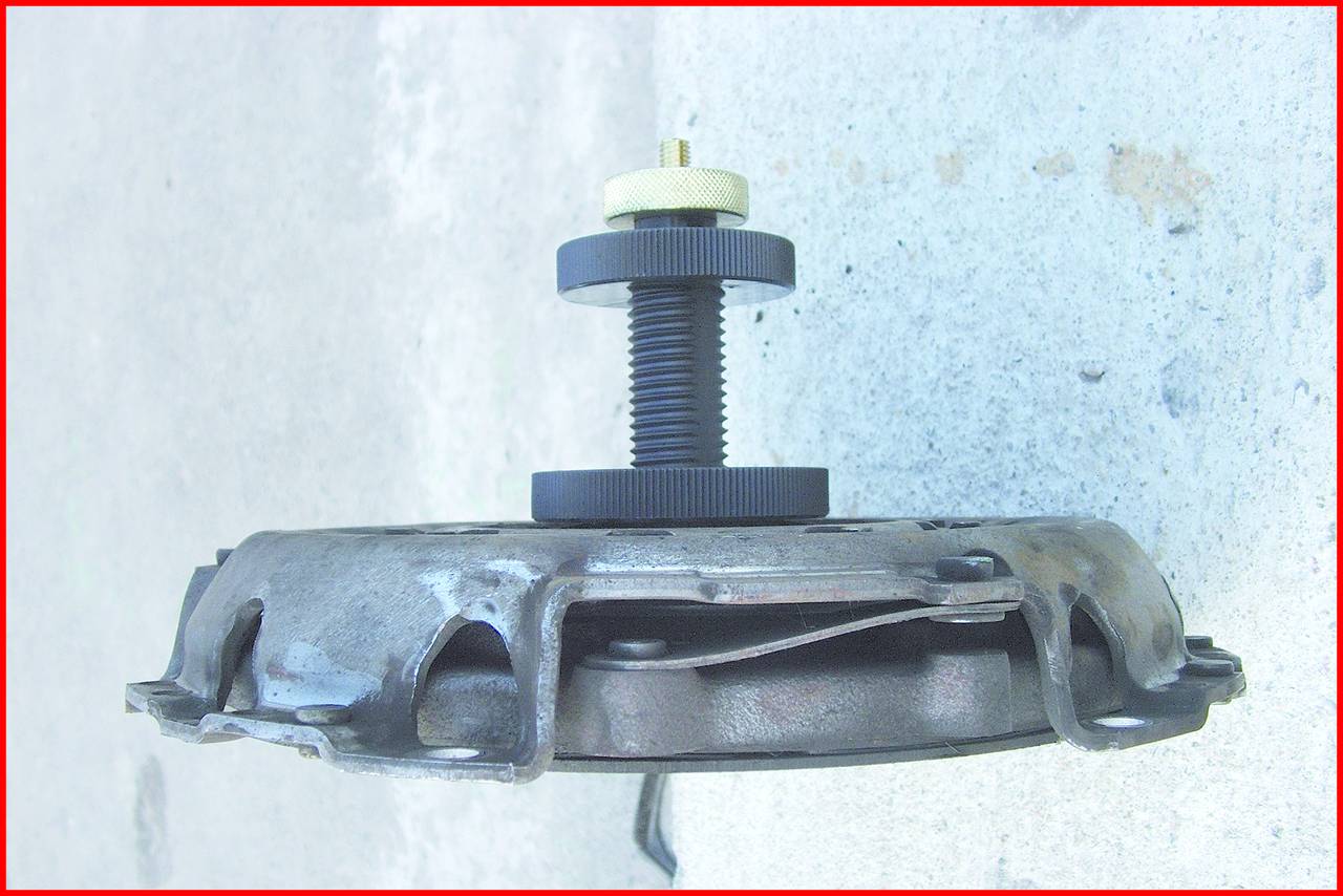 Dispositivo meccanico con una vite inserita in una piastra metallica circolare. Sembra essere un componente di un utensile.