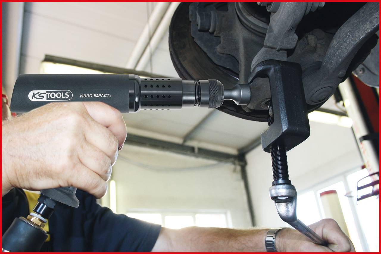 Una persona sta utilizzando un utensile pneumatico per serrare un cacciavite su un fissaggio di un componente auto; focus sullo strumento e sulla mano.