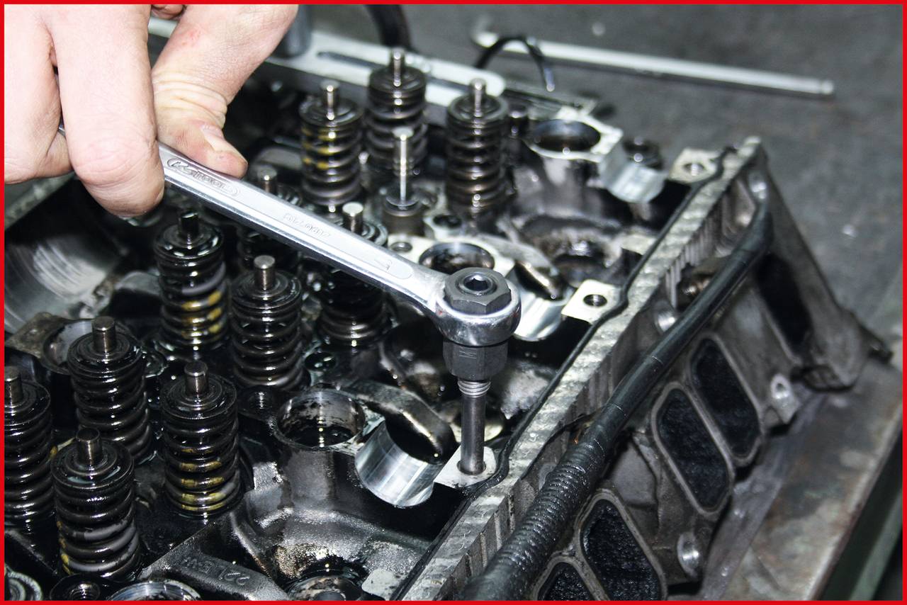 Una mano sta serrando una vite su un blocco motore con una chiave inglese, mostrando la riparazione di un'auto o la manutenzione del motore.