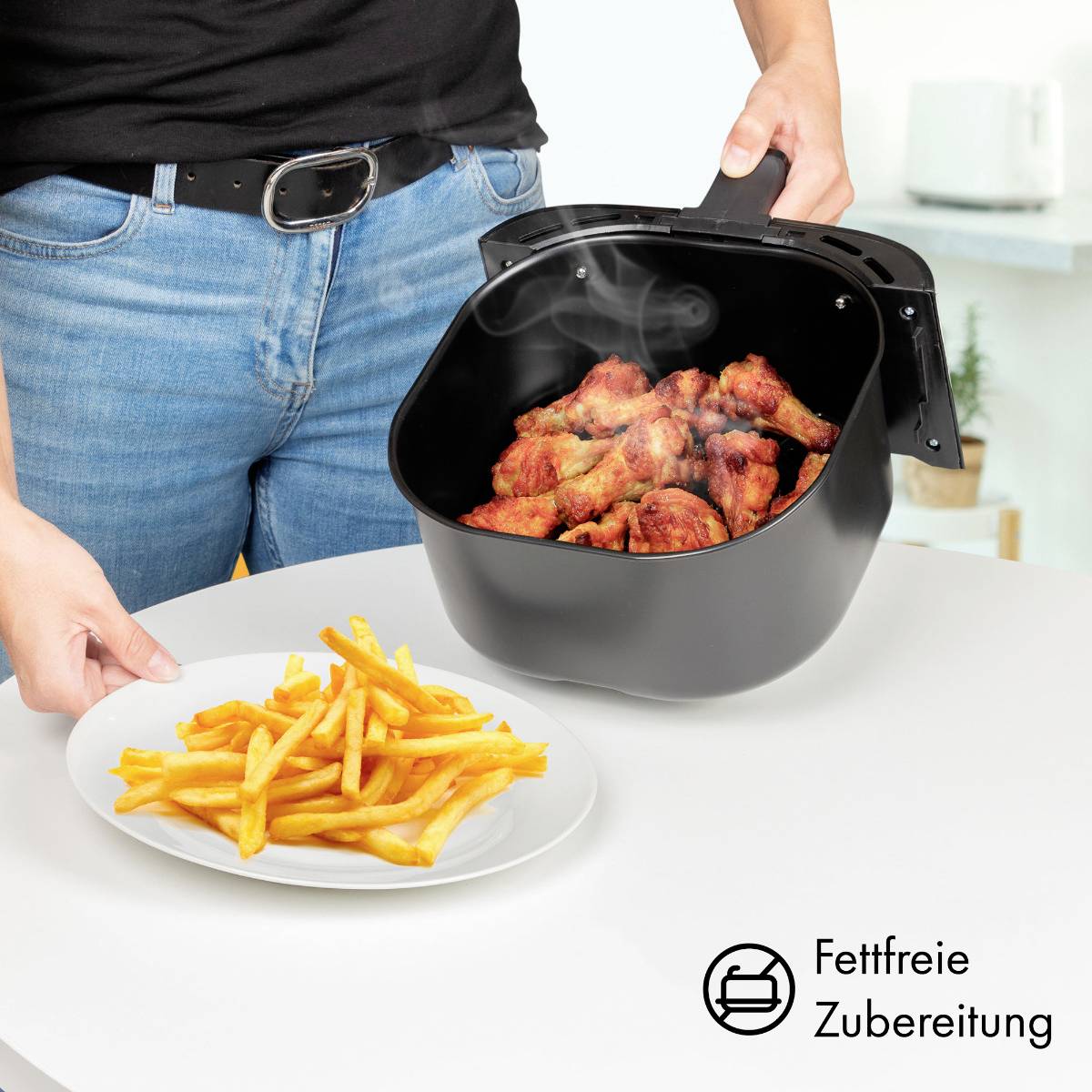 Una persona sta disponendo ali di pollo fritte e fumanti da una friggitrice su un piatto con patatine fritte, simboleggiando la cottura a basso contenuto di grassi.