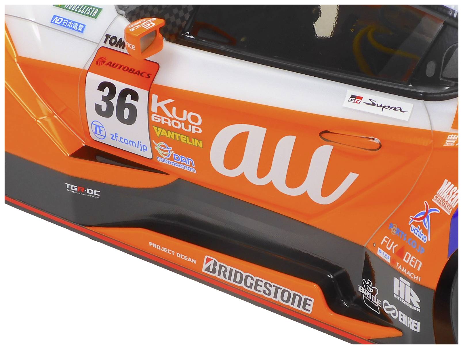 Vettura da corsa con verniciatura arancione e bianca e il numero di gara '36'. Loghi degli sponsor e dettagli tecnici visibili sul lato.