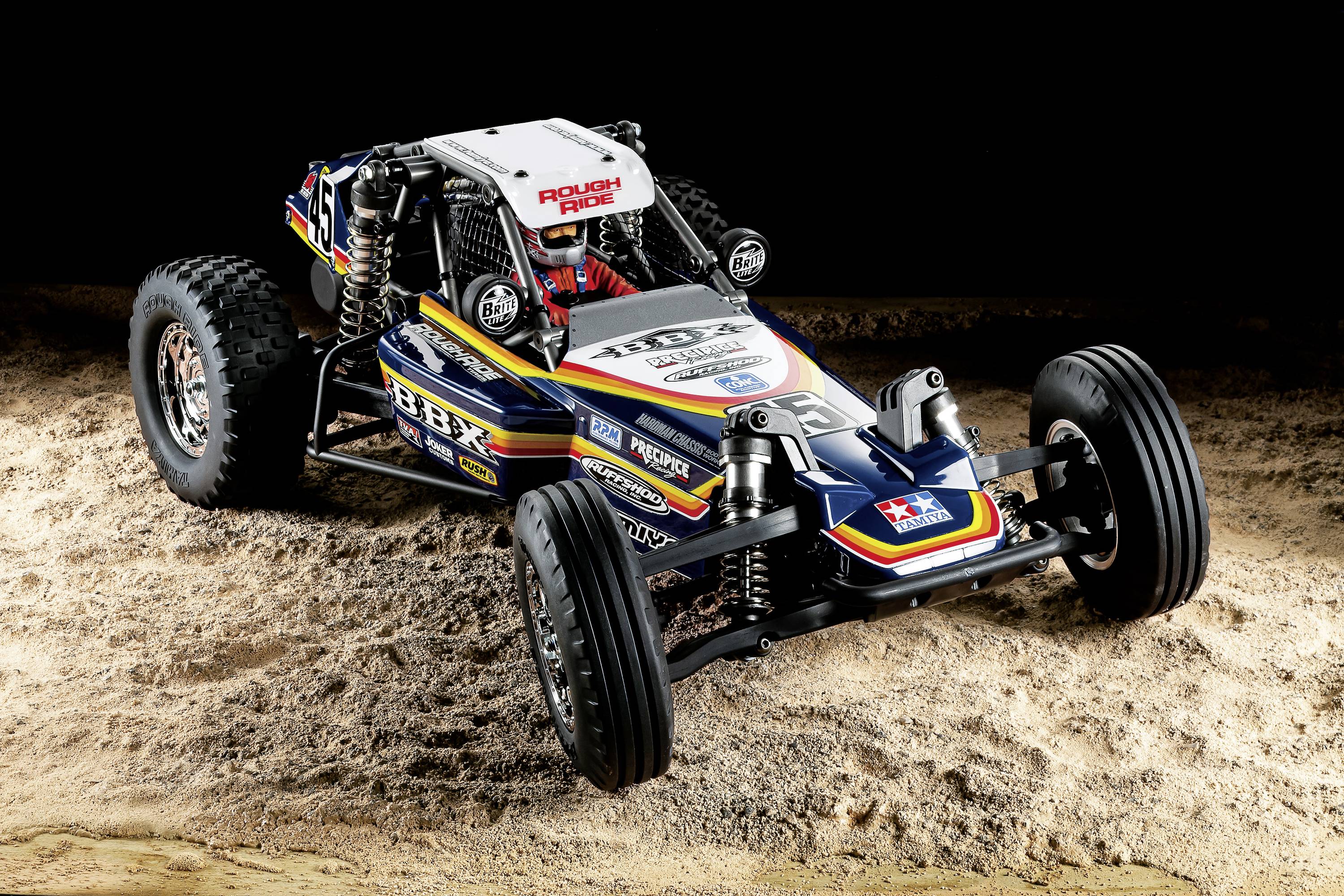 Buggy RC sfreccia sulla sabbia, coloratissimo e decorato con adesivi, in una scena di gara dinamica.