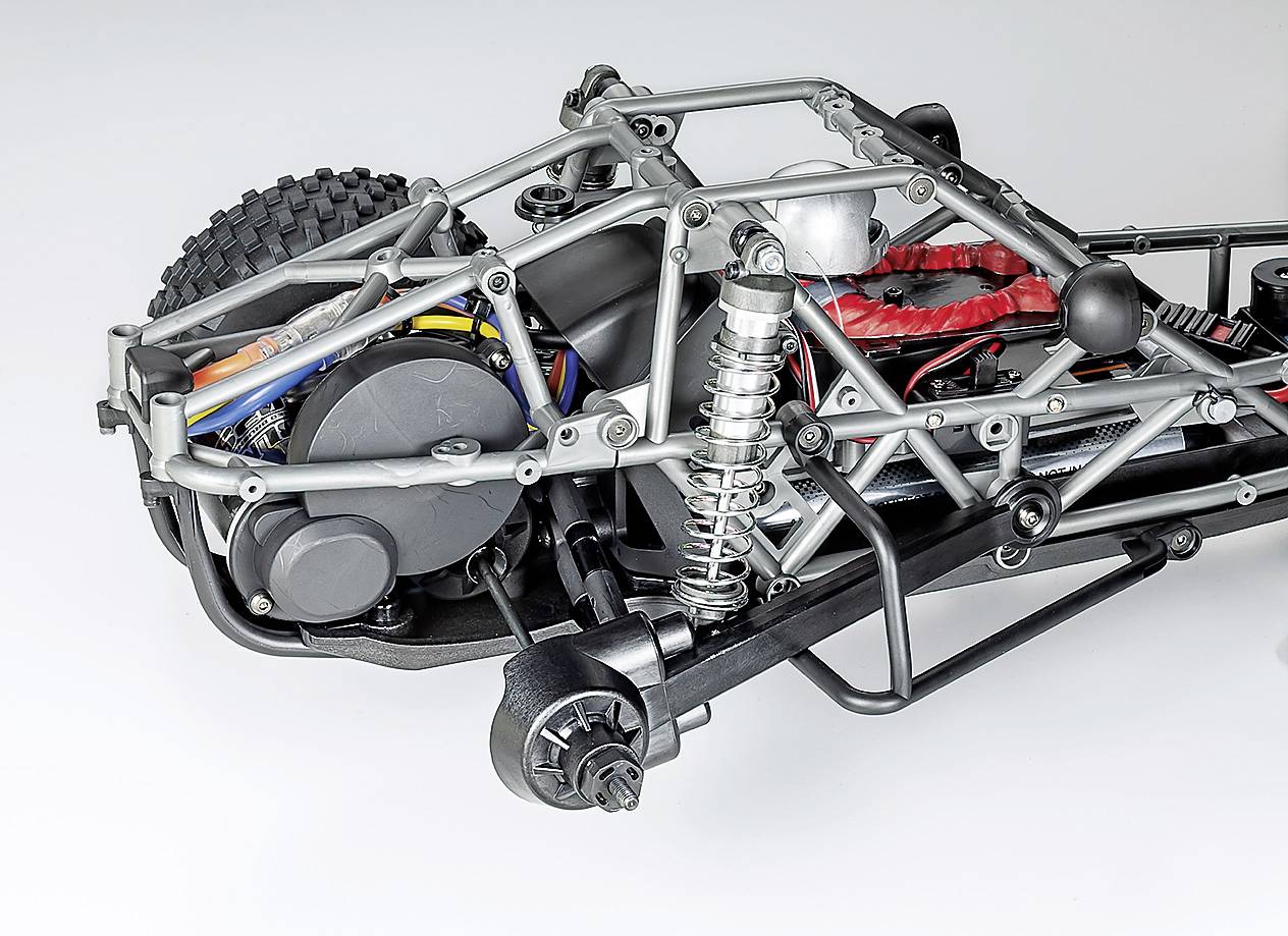 Un telaio di un'auto in miniatura mostra una sospensione complessa, il profilo dei pneumatici e un telaio in metallo, evidenziati da precise connessioni metalliche e cavi.