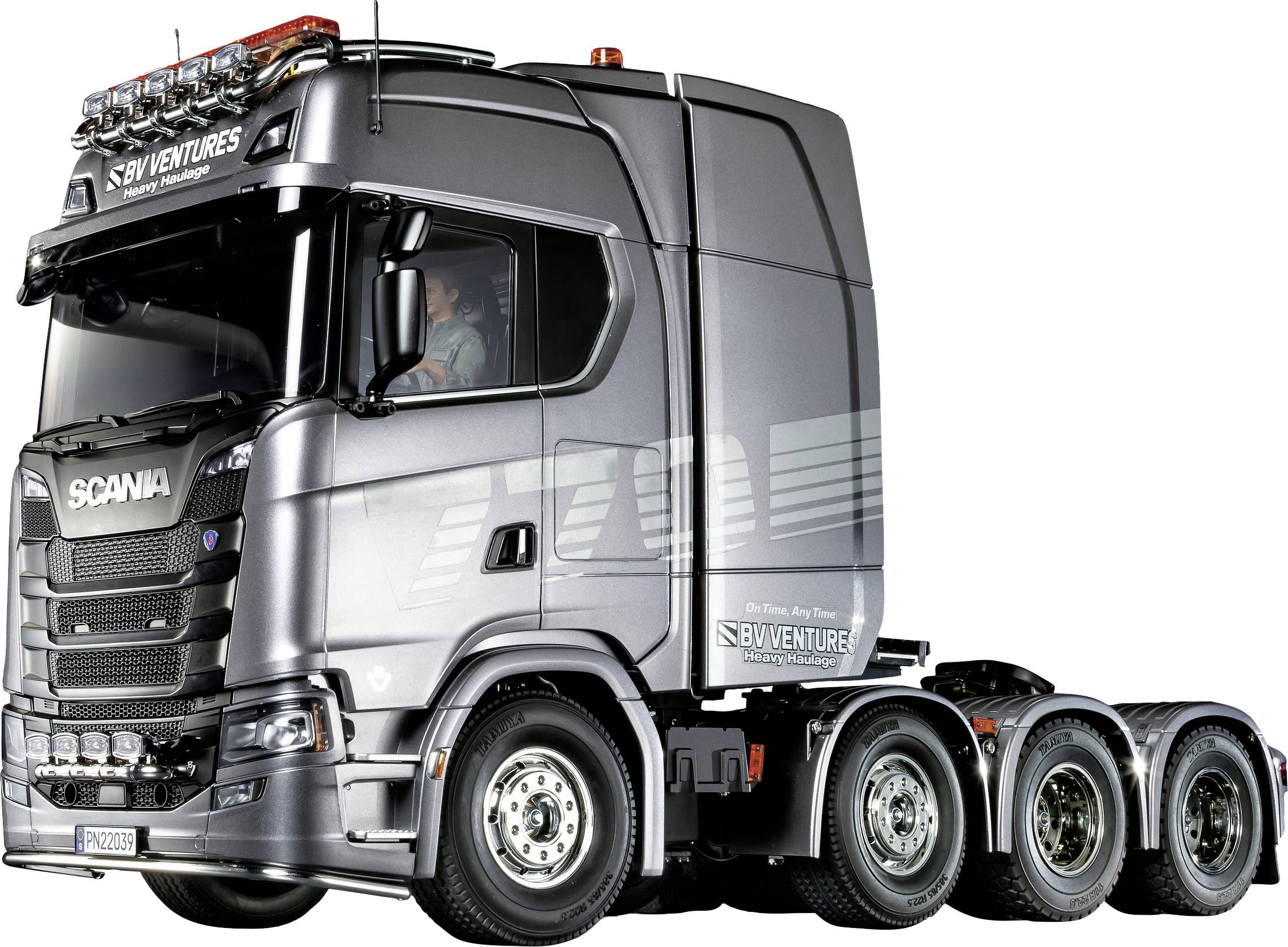 Camion con cabina d'argento, logo sulla portiera, che procede verso sinistra. Conducente visibile. Diversi assi per carichi pesanti.