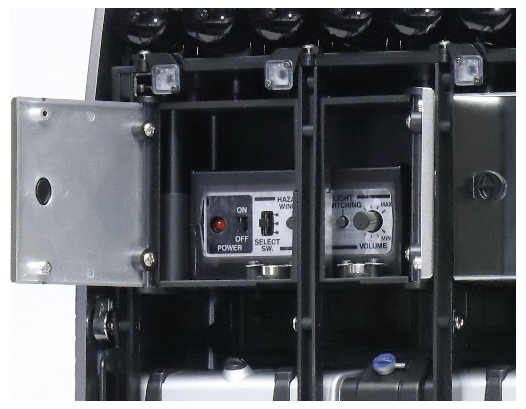 L'inquadratura mostra un pannello di controllo aperto di un dispositivo tecnico con interruttori e un display per la gestione delle funzioni.
