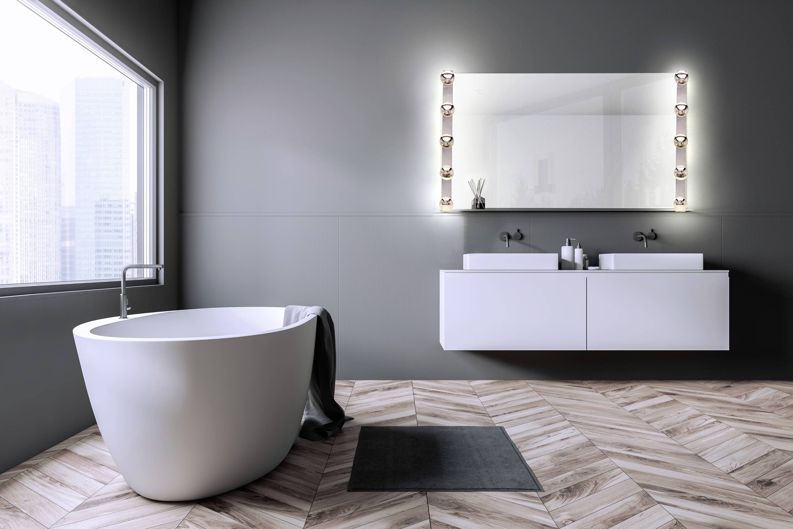 Bagno moderno con vasca da bagno freestanding, pavimento in legno, grande specchio e doppio lavabo.