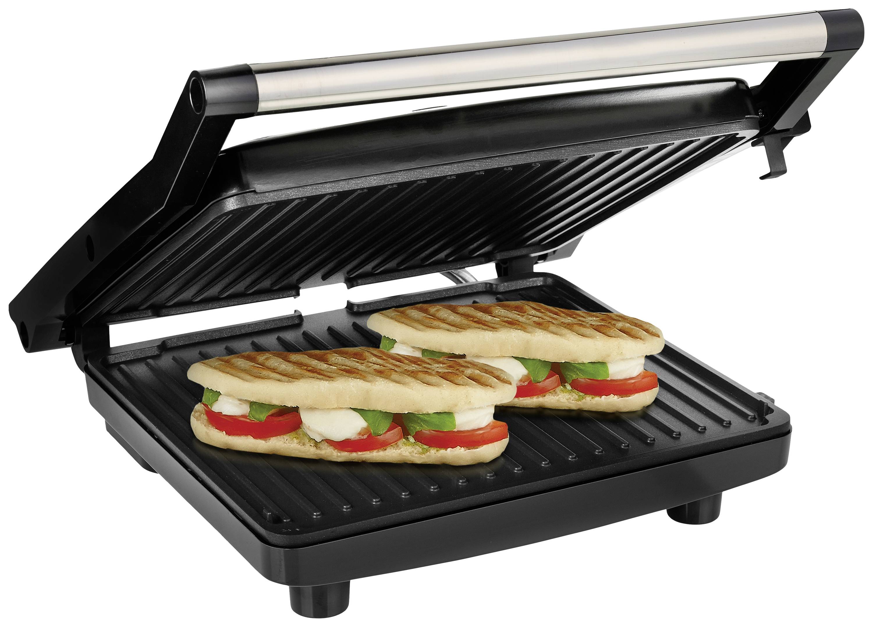 Un grill per panini aperto con due panini alla griglia, ripieni di pomodori, basilico e mozzarella.