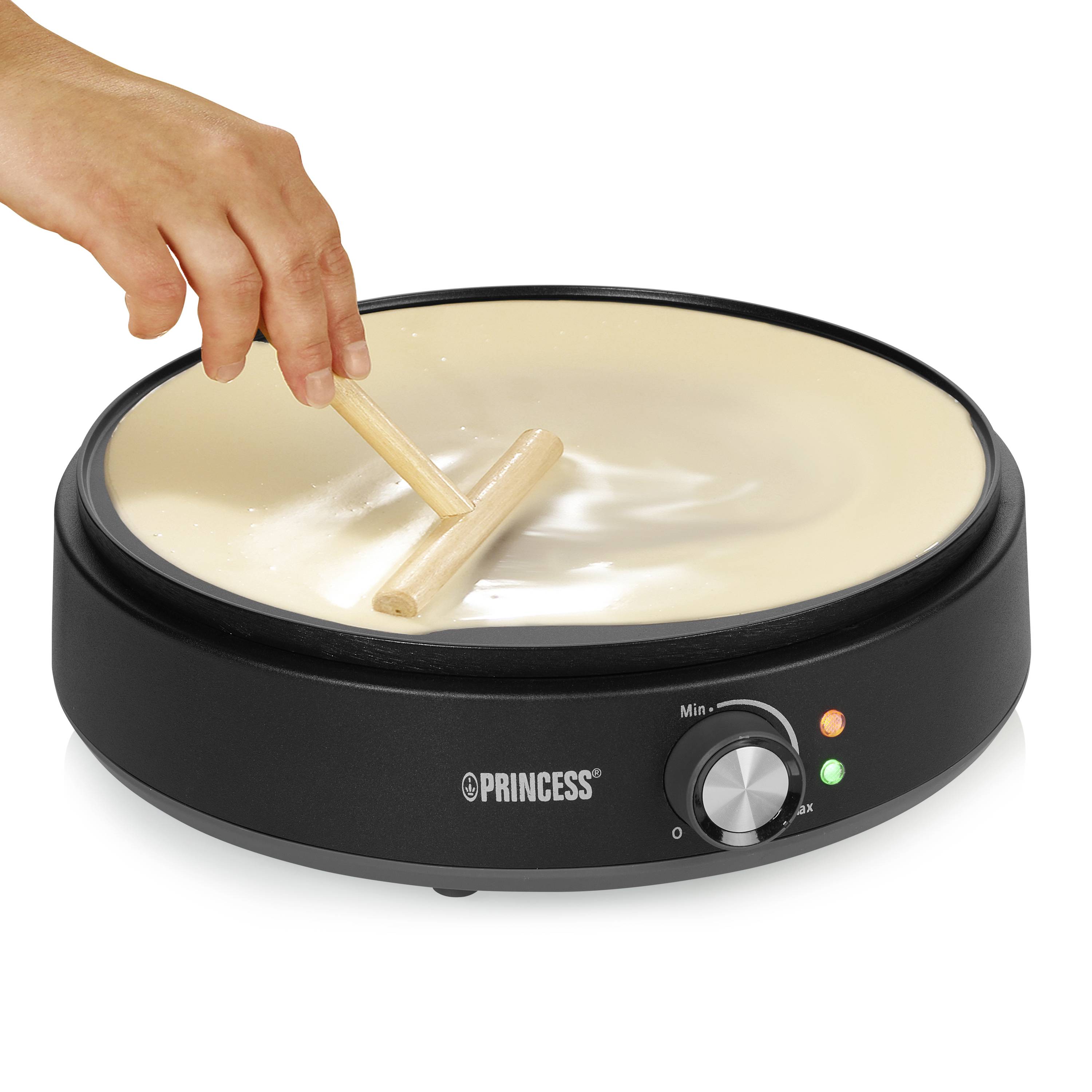 Una persona stende l'impasto con un mattarello su una macchina per crêpe rotonda e nera con regolatore di temperatura.