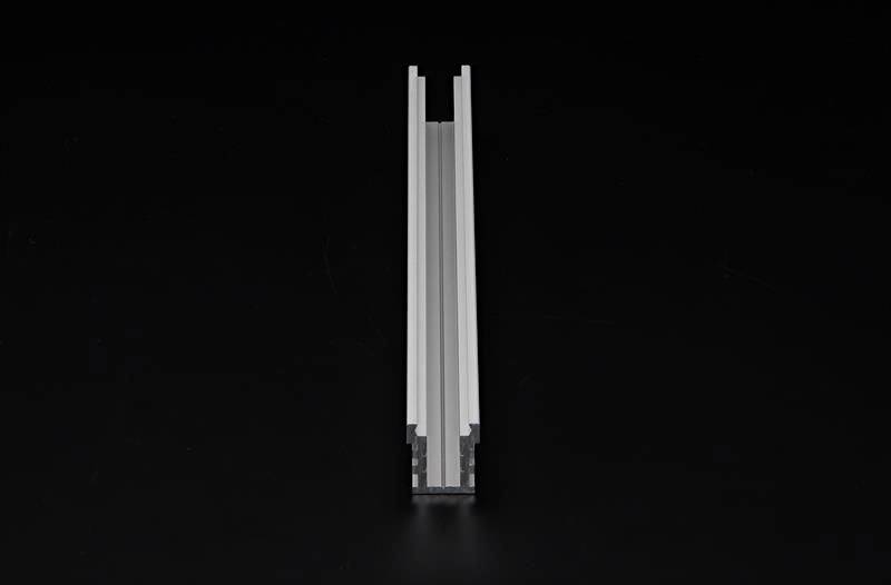 Un profilo in alluminio argentato su uno sfondo nero. Il profilo presenta una guida a forma di H, tipica delle applicazioni industriali.