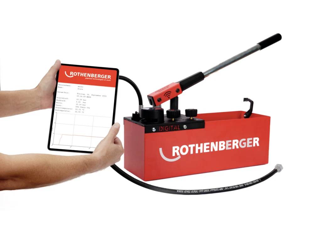 Pompa per test di pressione digitale di Rothenberger, con tablet collegato che mostra i risultati del test. Pompa rossa con impugnatura manuale e tubo.