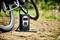 Un compressore elettrico è posizionato su un sentiero sterrato accanto a una bicicletta, pronto per gonfiare i pneumatici.