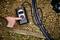 Una mano sta azionando un compressore d'aria digitale per gonfiare un pneumatico di bicicletta su un terreno sassoso.