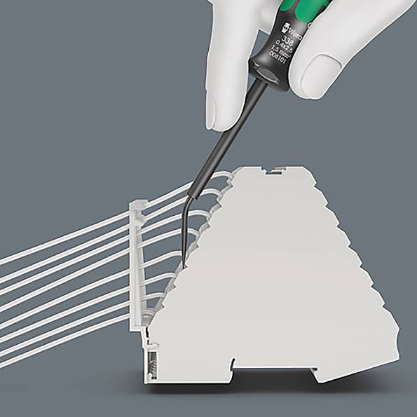Una mano tiene un cacciavite mentre fissa i fili in un morsetto a più piani, illustrando un processo di connessione elettrica.