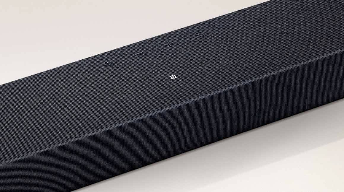 Una soundbar nera dal design minimalista. Dispone di tasti per il volume e l'alimentazione sulla parte superiore.