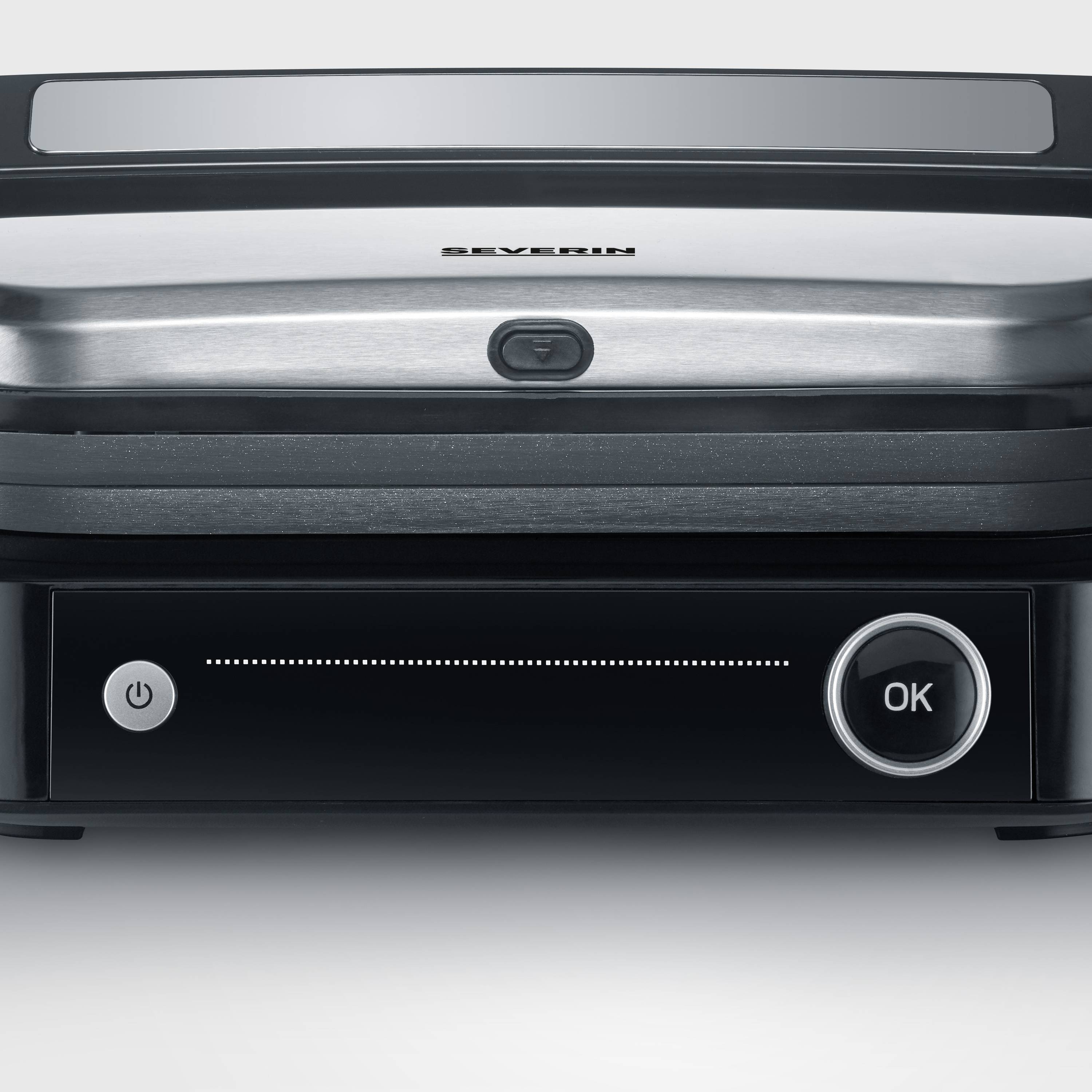 Un grill elettrico con superficie argentata e involucro nero. Sul davanti è presente un pulsante con la scritta 'OK'.