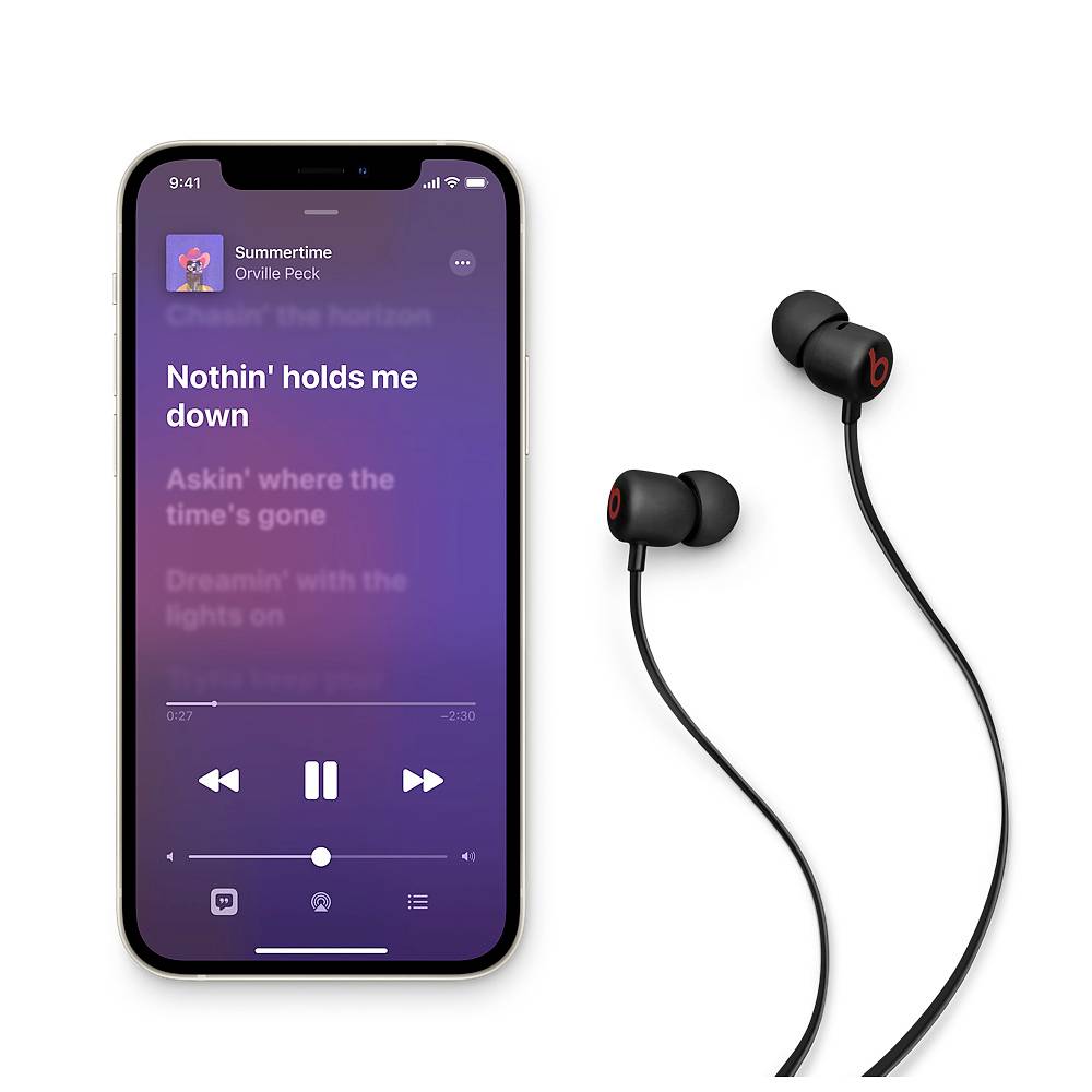 Uno smartphone mostra un lettore musicale che riproduce il brano 'Nothin' holds me down' di Orville Peck. Accanto ci sono degli auricolari neri in-ear.