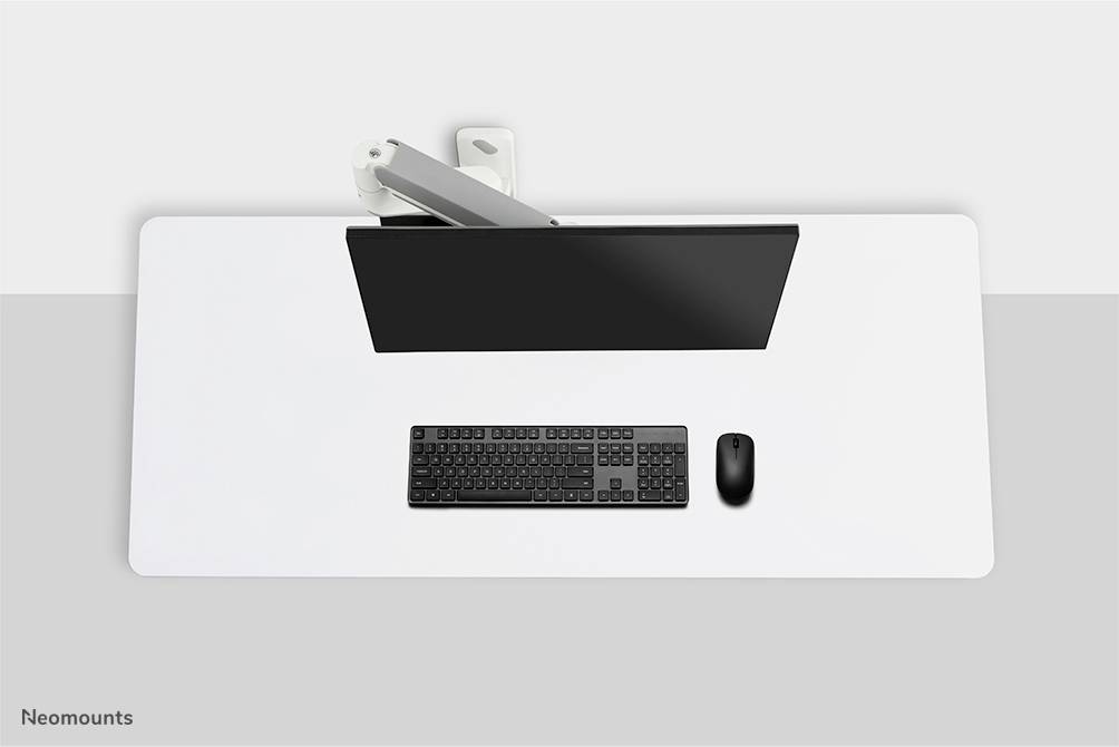 Un tavolo scrivania pulito con un monitor, una tastiera nera e un mouse, visto dall'alto. Design minimalista.