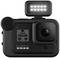 Una fotocamera GoPro con un'illuminazione LED montata sulla parte superiore, il display mostra '4K 60 W', '08', simboli per lo stato della batteria e della memoria.