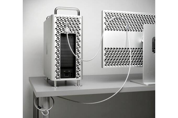 Custodia per computer con un motivo traforato, posizionata su una scrivania e collegata a un monitor dal design simile.