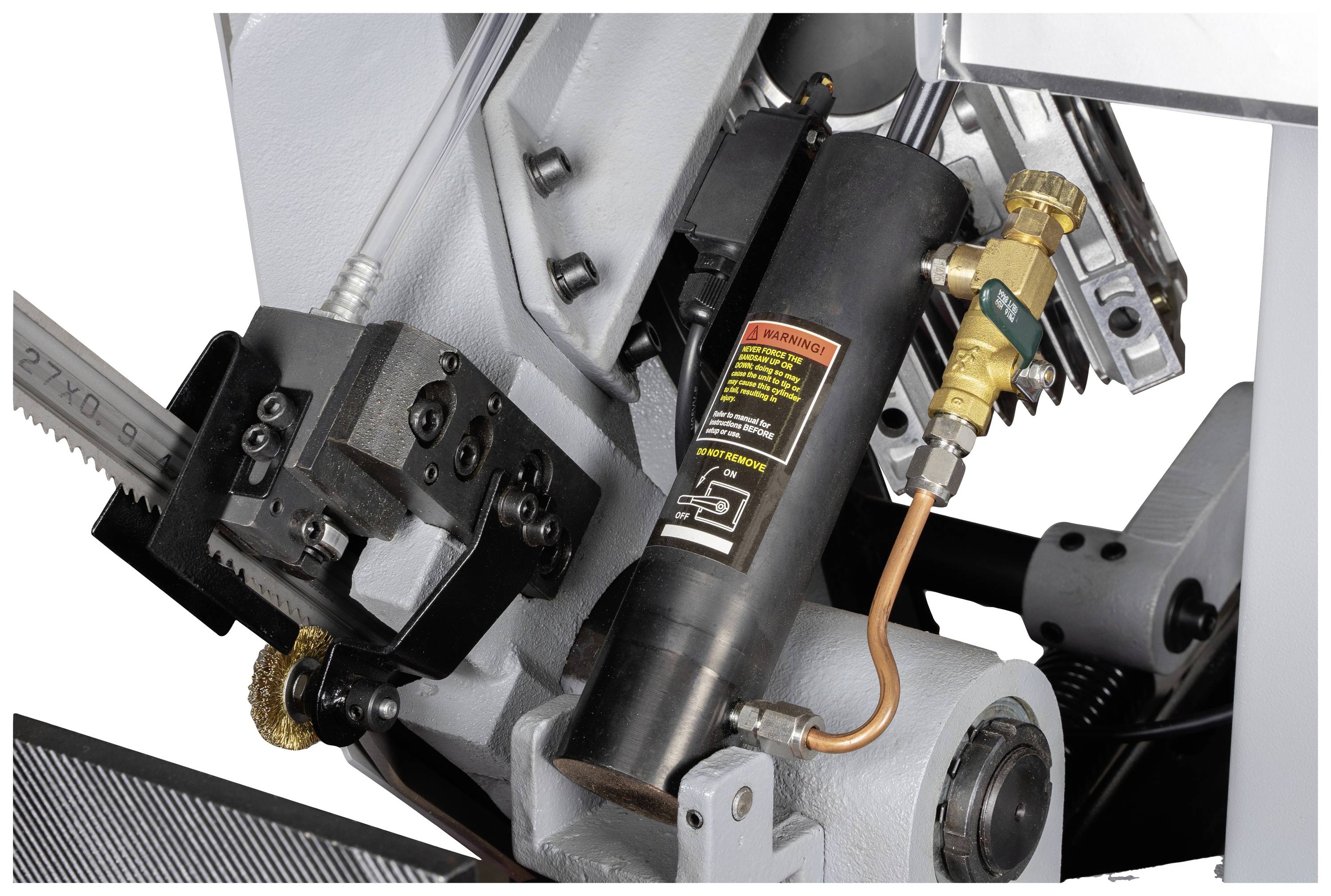 Primo piano di un componente idraulico di una sega a nastro con cilindri, leve e tubi flessibili.