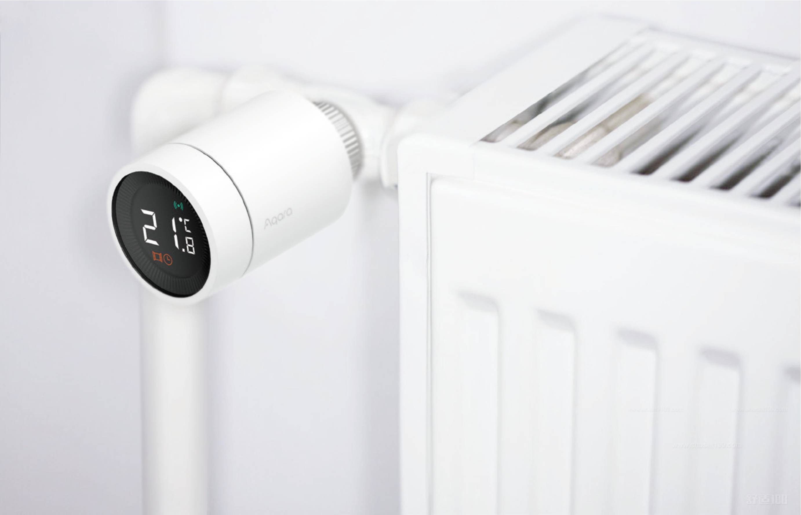 Un termostato mostra la temperatura di 21 gradi. È montato su un radiatore bianco e regola il riscaldamento.