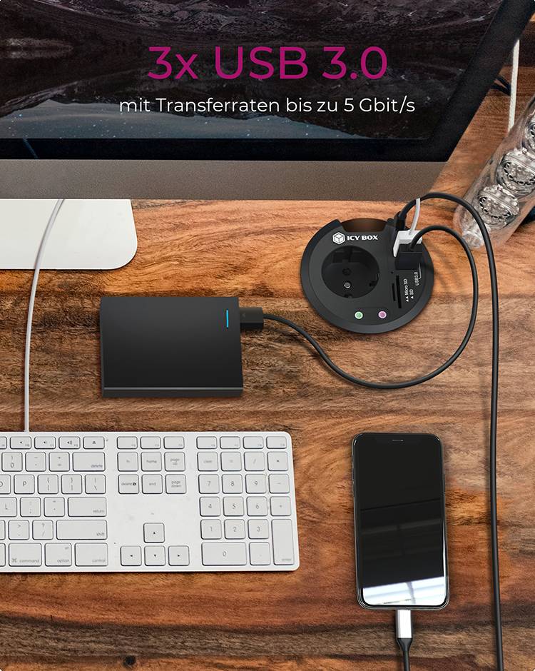 'Scrivania con computer, tastiera, hard disk esterno, smartphone e presa elettrica con porte USB.'