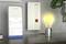 Lampada Zigbee controllata da uno smartphone, accanto a una lampadina illuminata sul tavolo, e router FRITZ!Box sulla parete.