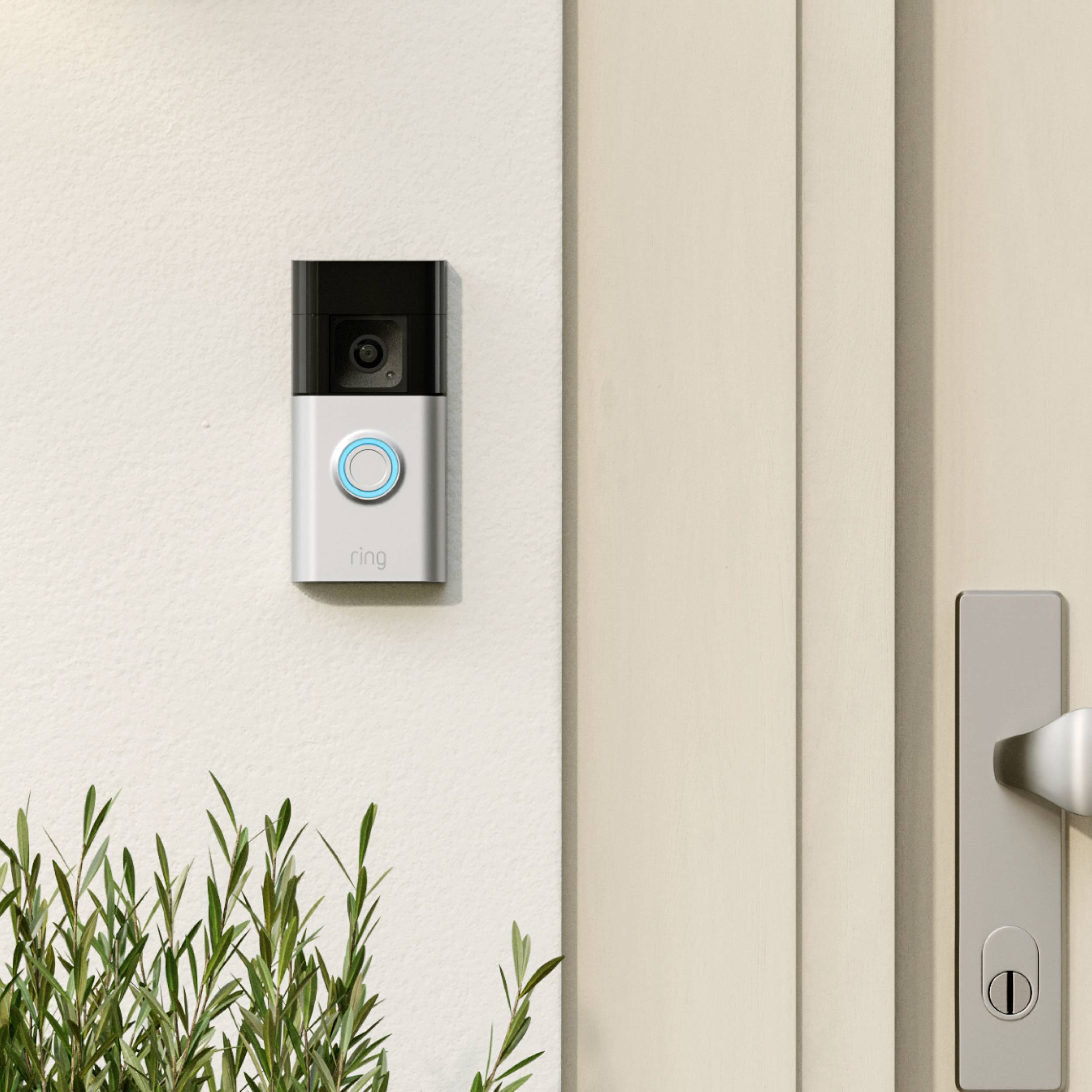 Un campanello intelligente con telecamera e un anello LED blu è installato accanto a una porta d'ingresso. Accanto ad esso è visibile una maniglia della porta.