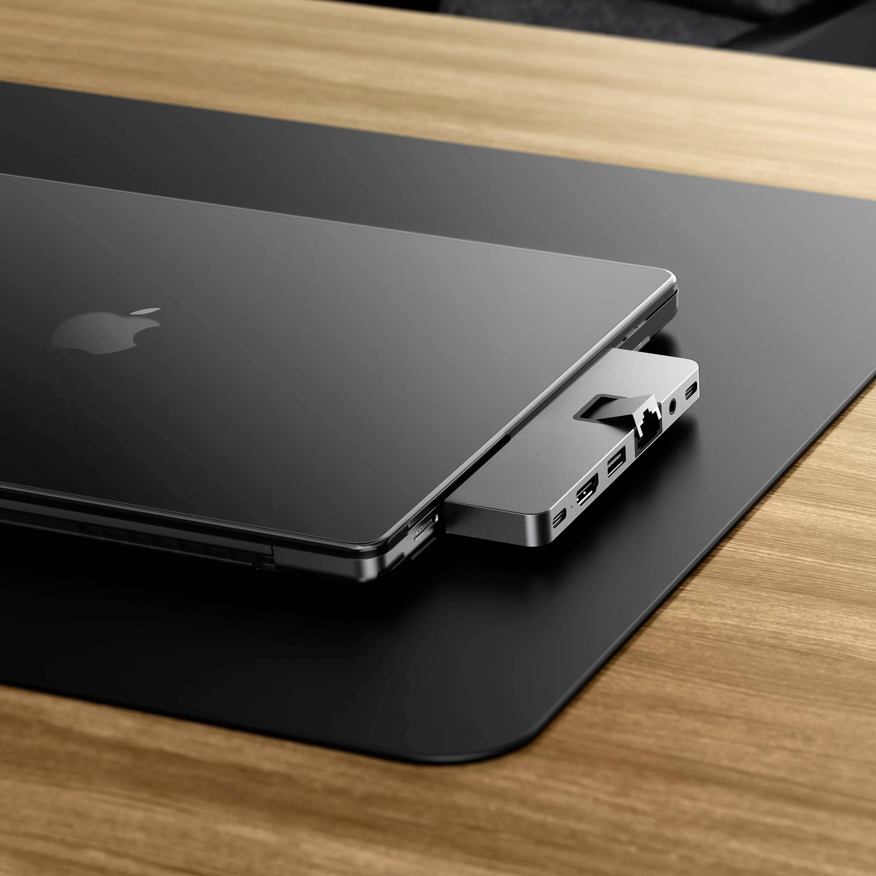 Un laptop sottile su un tavolo con un adattatore collegato che offre diverse porte, inclusi porte USB e HDMI.