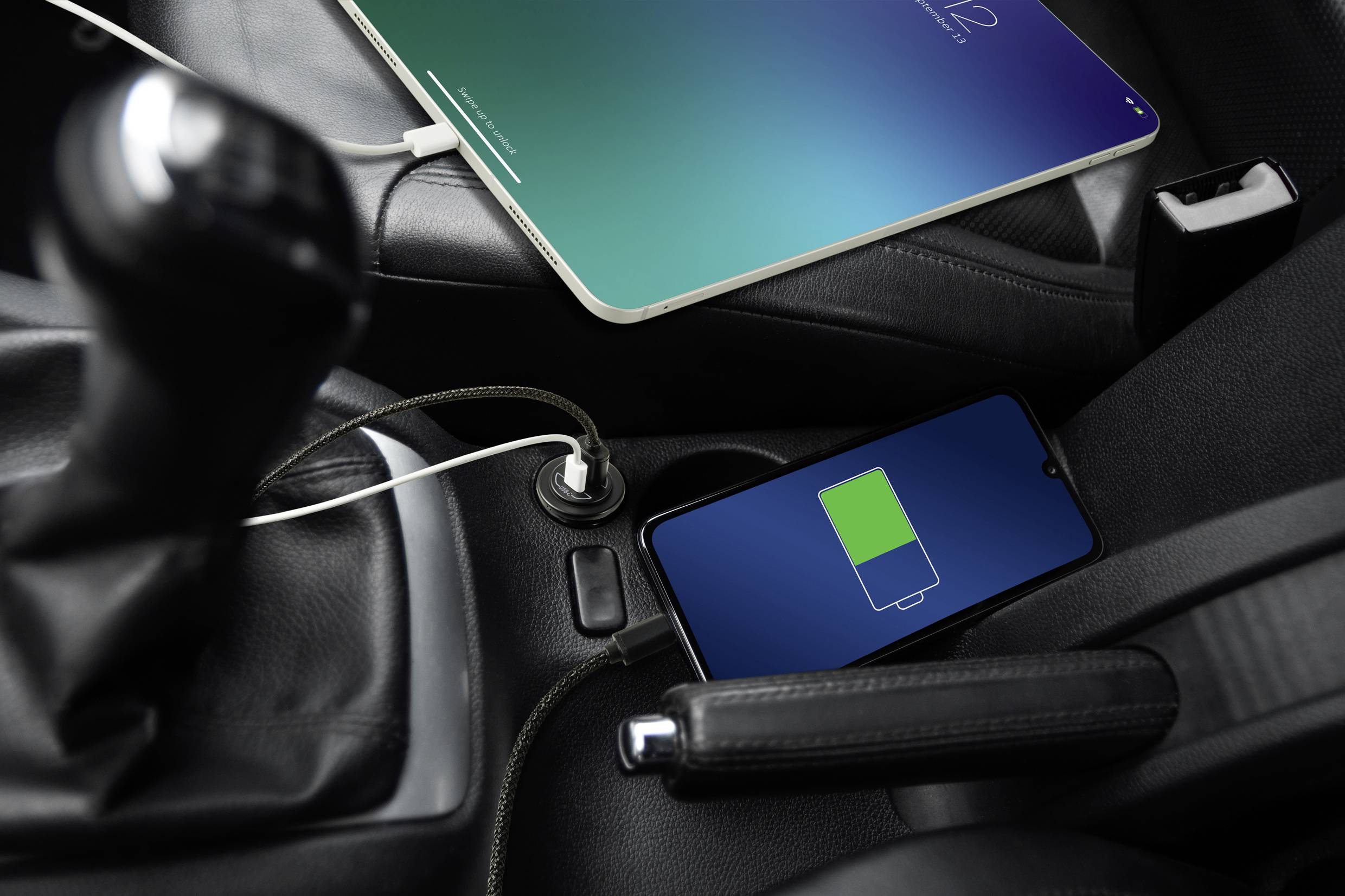 Un cellulare e un tablet vengono caricati in auto. Il cellulare mostra il simbolo di ricarica.