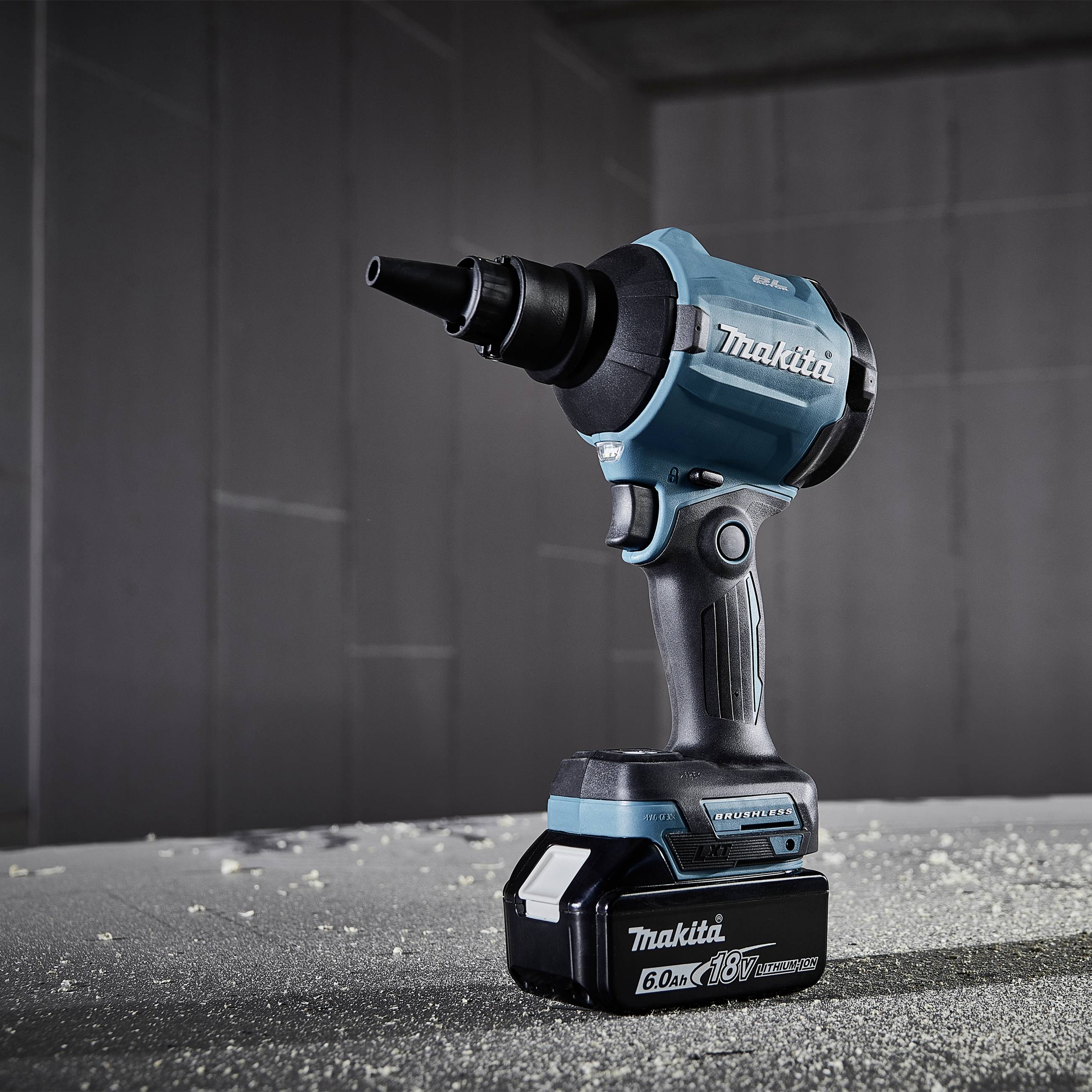 Trapano avvitatore Makita 18V su superficie polverosa; sullo sfondo un muro grigio. Ideale per lavori artigianali.