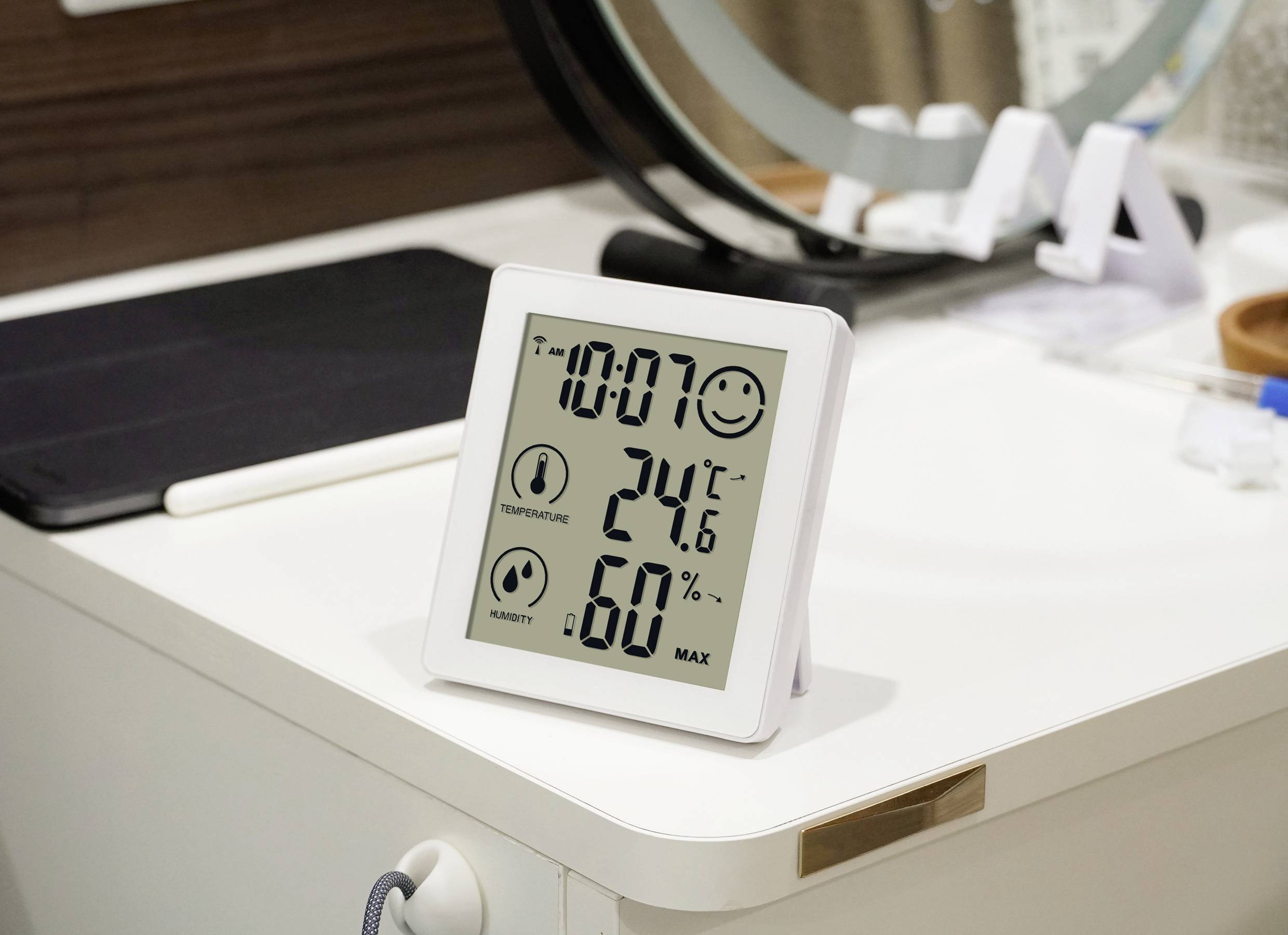 Un igrometro digitale su un tavolo mostra l'ora 10:07, temperatura 24,6°C e umidità del 60%.