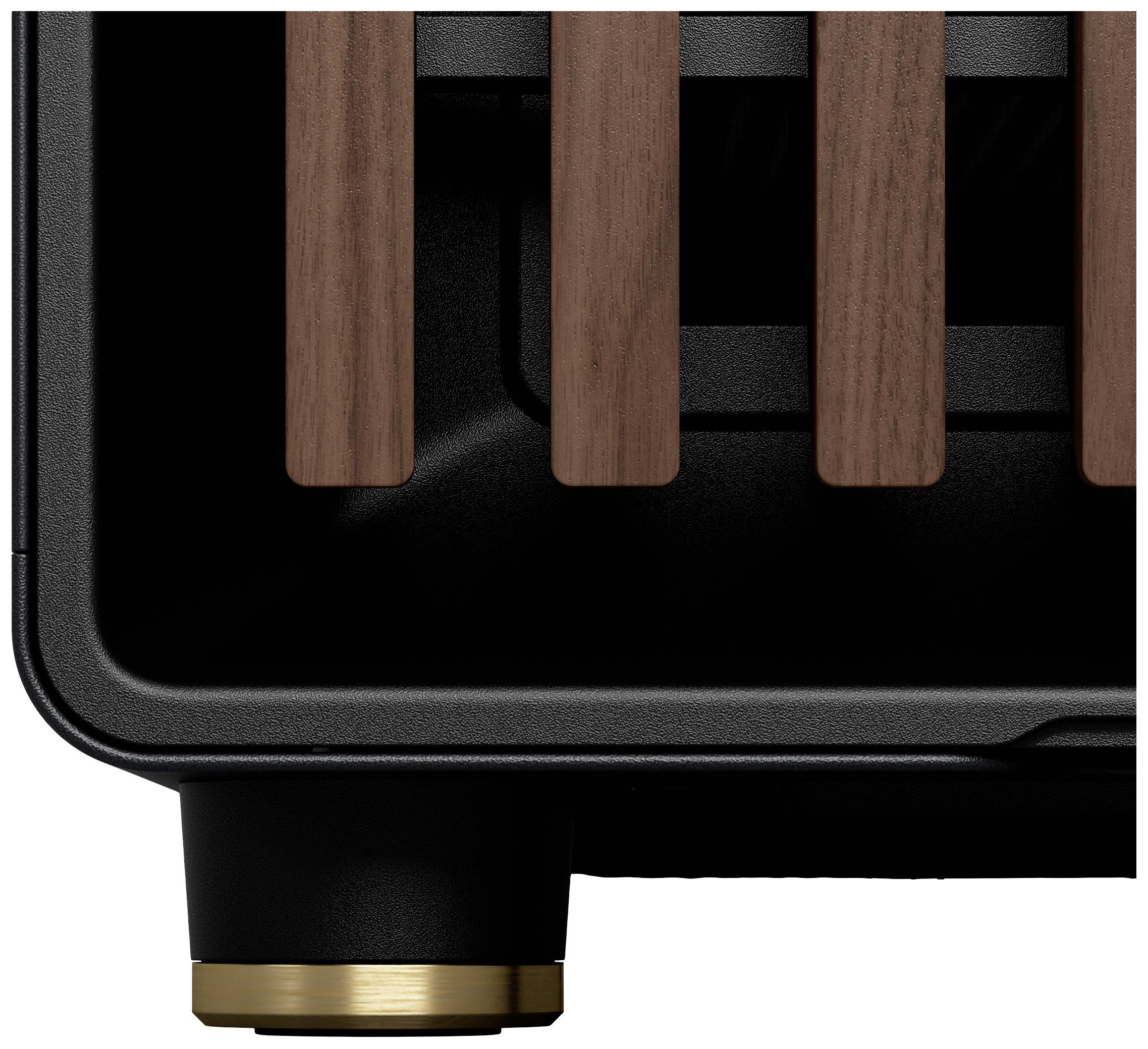 Primo piano di un involucro nero per dispositivi con listelli verticali in legno e un elemento decorativo dorato alla base.